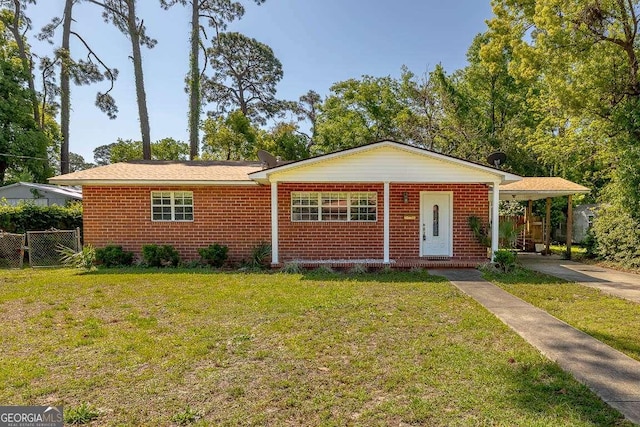 view of front of house with a front yard, a carport, fence, brick siding, and driveway