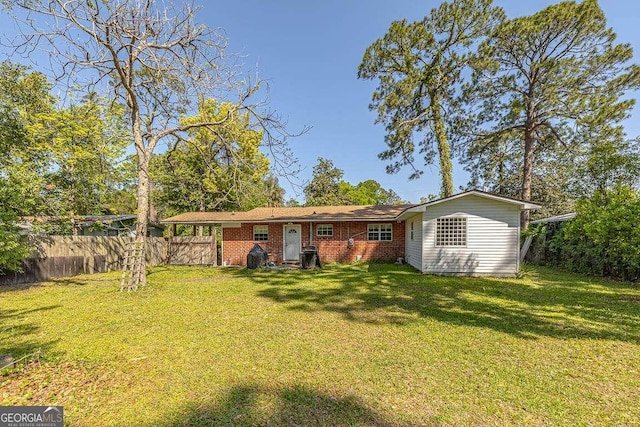 rear view of house featuring a yard, fence, and brick siding