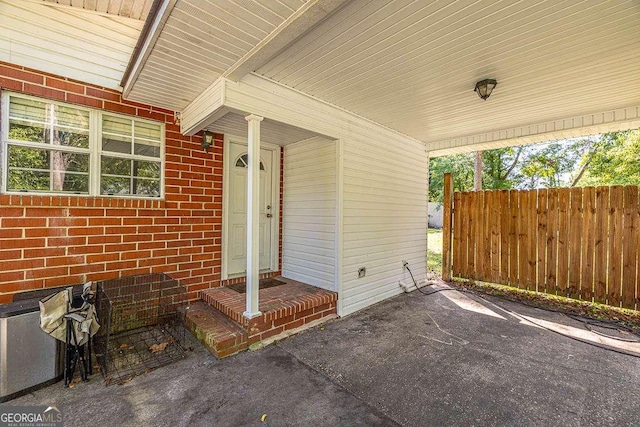 view of exterior entry with brick siding and fence