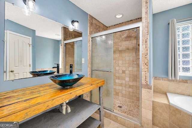 full bath featuring a textured ceiling, a sink, and a stall shower
