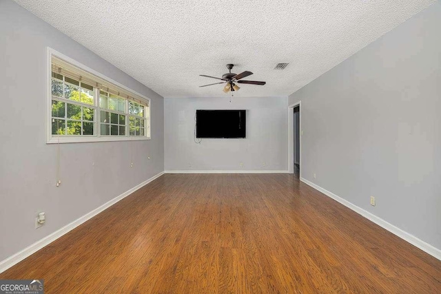 spare room featuring baseboards, a textured ceiling, visible vents, ceiling fan, and wood finished floors
