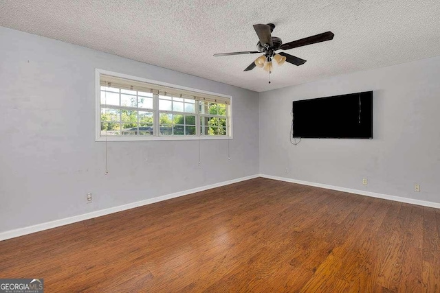 empty room with ceiling fan, baseboards, wood finished floors, and a textured ceiling