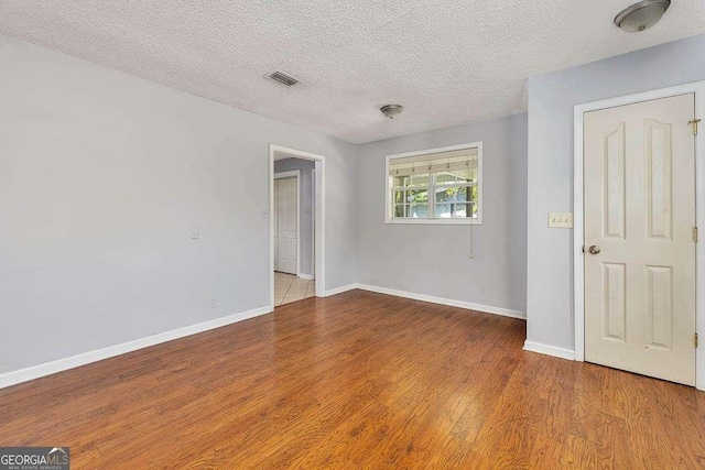 interior space with visible vents, baseboards, wood finished floors, and a textured ceiling