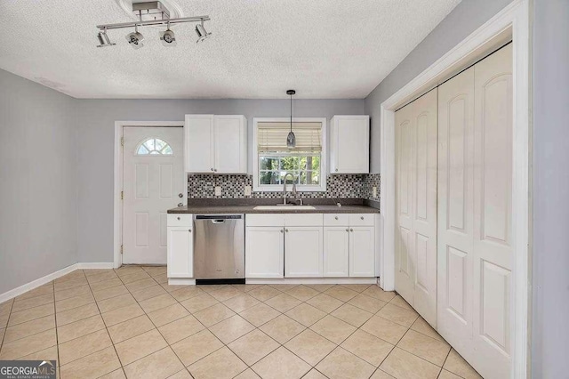kitchen featuring stainless steel dishwasher, tasteful backsplash, white cabinetry, a sink, and dark countertops