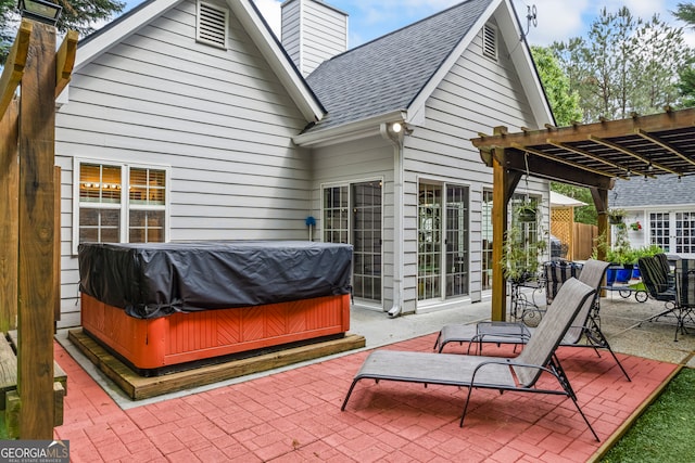 back of property featuring a chimney, a patio area, a pergola, and a hot tub