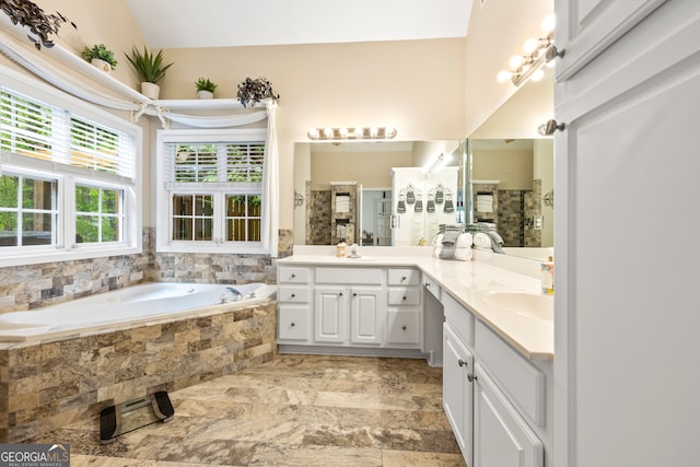 full bath featuring a tile shower, a bath, a sink, and double vanity