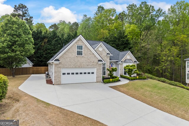 craftsman house featuring a garage, a front yard, stone siding, fence, and driveway