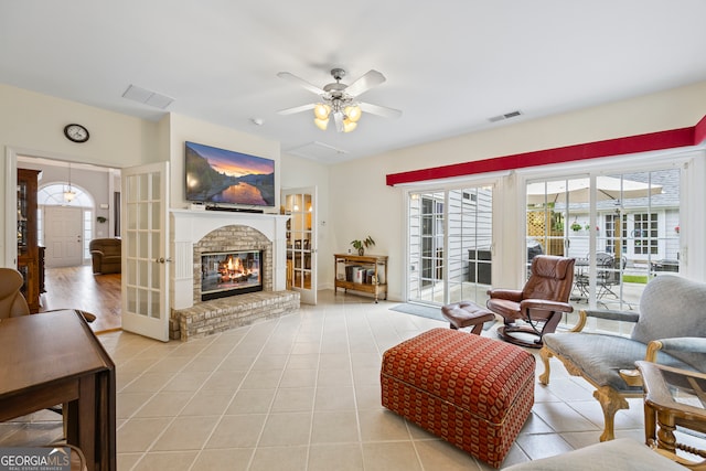 living area with visible vents, ceiling fan, light tile patterned floors, and a fireplace