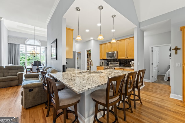 kitchen with a breakfast bar, a peninsula, light wood-style floors, appliances with stainless steel finishes, and a sink