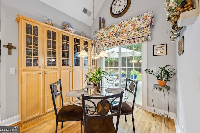 dining space with high vaulted ceiling, visible vents, baseboards, and light wood-style flooring