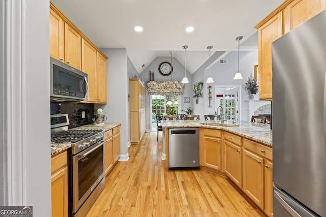 kitchen featuring tasteful backsplash, a sink, light wood-type flooring, a peninsula, and stainless steel appliances