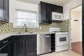 5672 Kingsport Dr Unit 4, Atlanta, GA 30342 - kitchen with white appliances, dark cabinets, light countertops, light tile patterned floors, and tasteful backsplash
