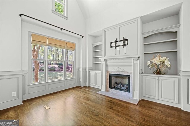 411 River Bluff Ln, Ball Ground, GA 30107 - unfurnished living room with wainscoting, built in shelves, dark wood-style flooring, and a premium fireplace
