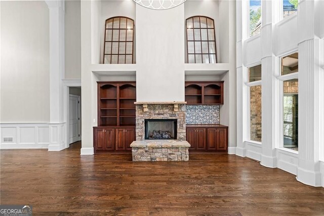 411 River Bluff Ln, Ball Ground, GA 30107 - unfurnished living room featuring a stone fireplace, a high ceiling, visible vents, a decorative wall, and wood finished floors