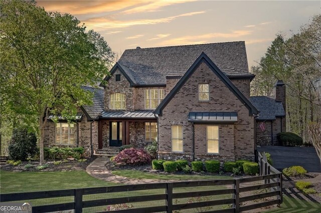 411 River Bluff Ln, Ball Ground, GA 30107 - tudor-style house with a fenced front yard, a front lawn, and brick siding