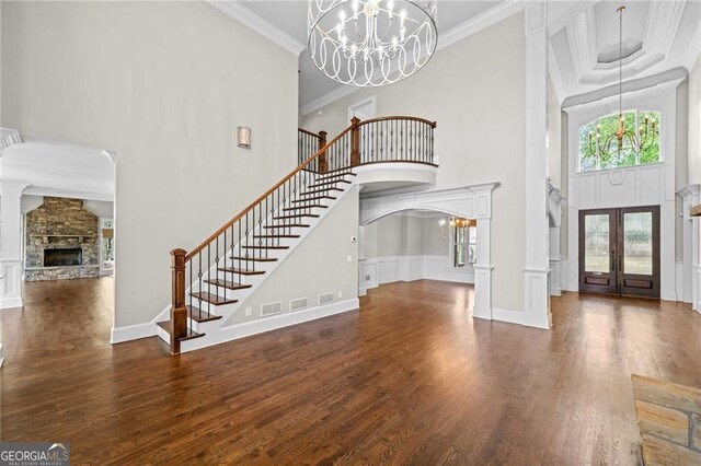 411 River Bluff Ln, Ball Ground, GA 30107 - foyer entrance with an inviting chandelier, a stone fireplace, wood finished floors, a towering ceiling, and stairs
