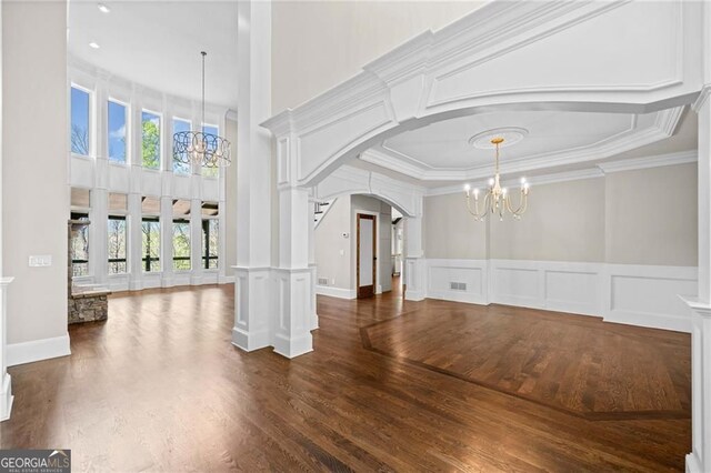 411 River Bluff Ln, Ball Ground, GA 30107 - unfurnished living room featuring arched walkways, a decorative wall, a notable chandelier, and dark wood-style floors