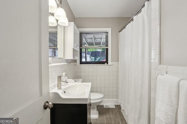 bathroom with tile walls, toilet, a wainscoted wall, vanity, and wood finished floors