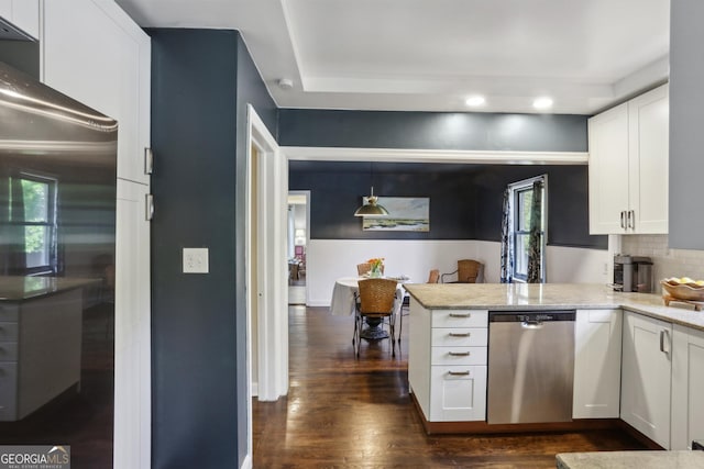 kitchen with appliances with stainless steel finishes, white cabinetry, dark wood-type flooring, a peninsula, and light stone countertops