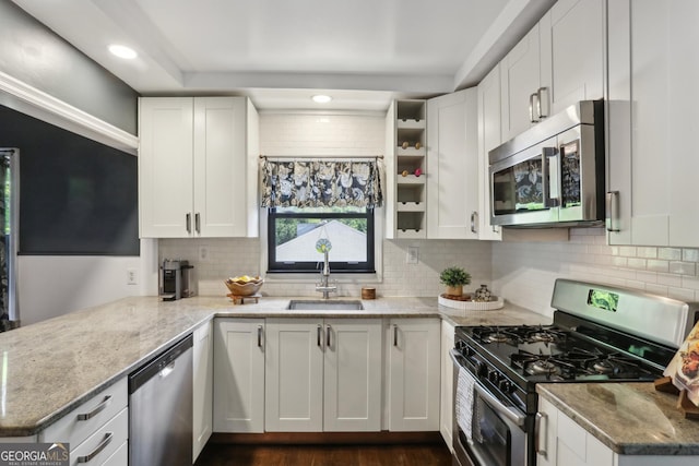 kitchen featuring appliances with stainless steel finishes, a sink, backsplash, white cabinetry, and recessed lighting