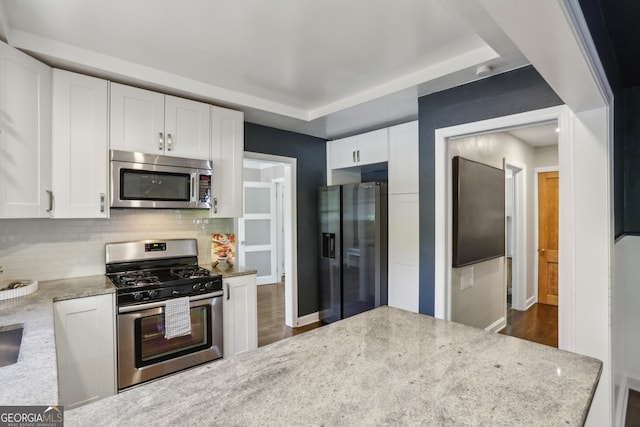 kitchen with appliances with stainless steel finishes, white cabinetry, tasteful backsplash, and dark wood-type flooring