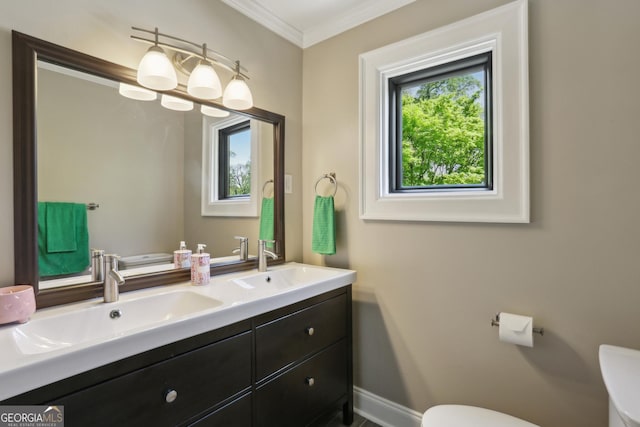 bathroom featuring toilet, ornamental molding, double vanity, and baseboards