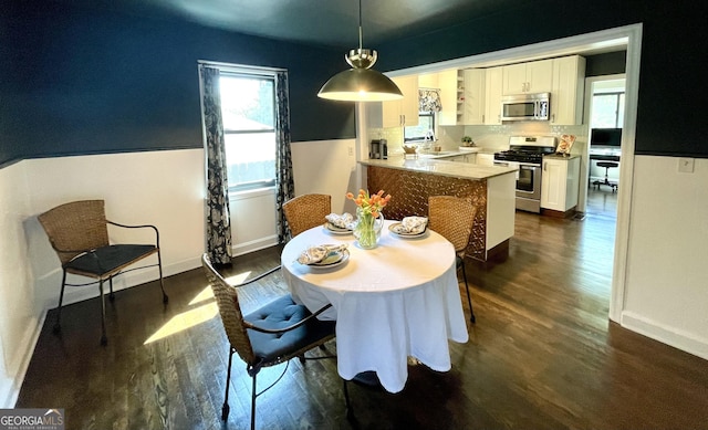 dining space featuring dark wood-style flooring and baseboards