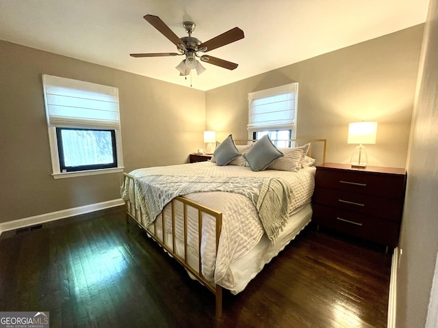 bedroom with dark wood finished floors, multiple windows, and baseboards