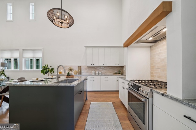 135 Channing Ln, Fayetteville, GA 30214 - kitchen featuring appliances with stainless steel finishes, a high ceiling, backsplash, light stone counters, and a center island with sink