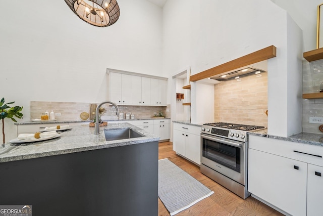 135 Channing Ln, Fayetteville, GA 30214 - kitchen with stainless steel gas range oven, backsplash, light wood-style flooring, white cabinetry, and light stone counters
