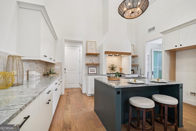 135 Channing Ln, Fayetteville, GA 30214 - kitchen with light wood-type flooring, backsplash, light stone counters, a high ceiling, and white cabinets
