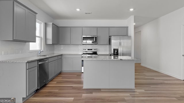 kitchen with visible vents, gray cabinets, appliances with stainless steel finishes, a sink, and light wood finished floors