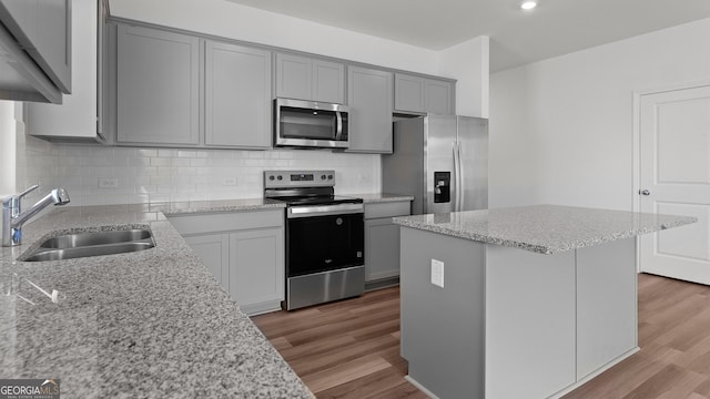 kitchen with gray cabinets, appliances with stainless steel finishes, decorative backsplash, and a sink