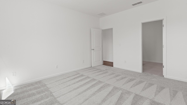 unfurnished bedroom with visible vents, baseboards, a walk in closet, and carpet floors
