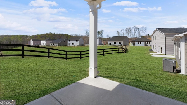 view of yard with a residential view, central AC, and fence