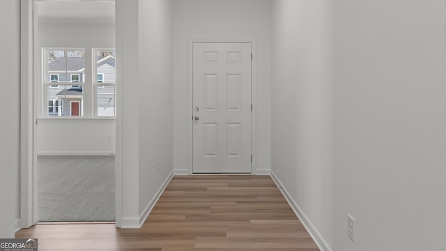 doorway with baseboards and light wood-style floors