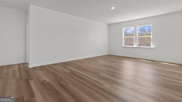 empty room with recessed lighting, baseboards, and wood finished floors
