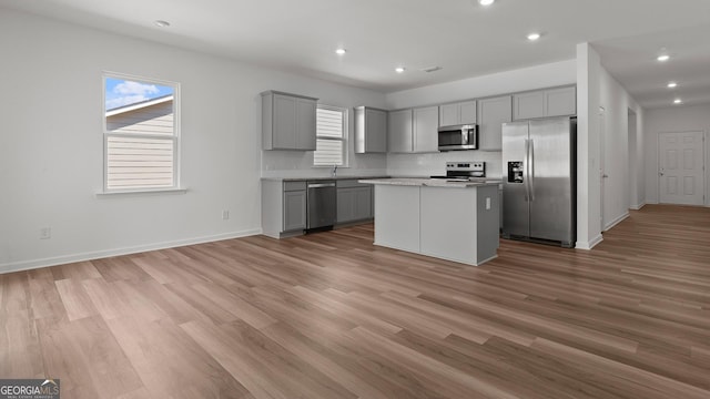 kitchen with gray cabinets, a center island, light wood-style floors, and stainless steel appliances