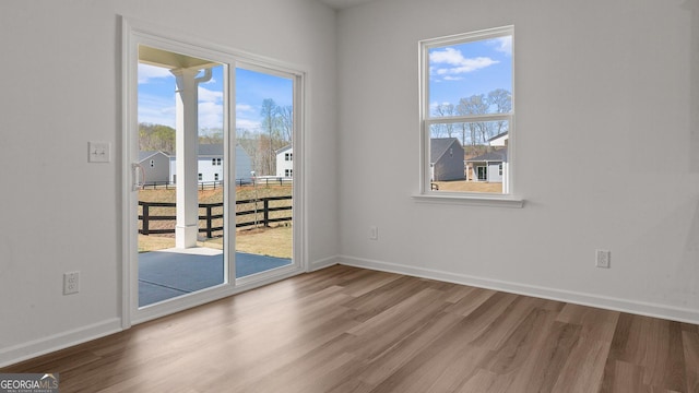 interior space with wood finished floors, baseboards, and a wealth of natural light