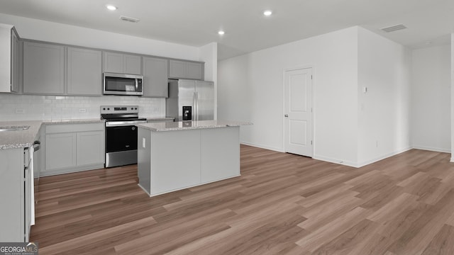 kitchen featuring stainless steel appliances, gray cabinetry, tasteful backsplash, and a center island