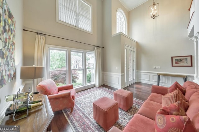 living area with plenty of natural light, wainscoting, a towering ceiling, and wood finished floors