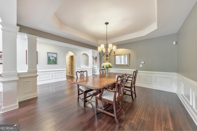 dining room with ornamental molding, wainscoting, a raised ceiling, a chandelier, and arched walkways
