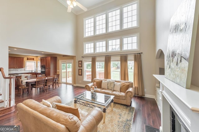 living room featuring a fireplace with flush hearth, a high ceiling, ceiling fan, and crown molding