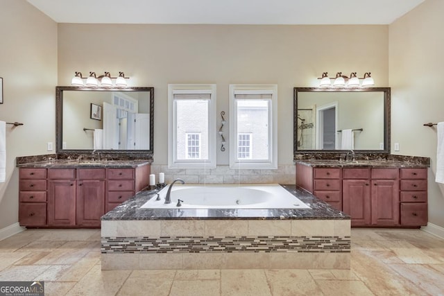 bathroom with a whirlpool tub, baseboards, and two vanities