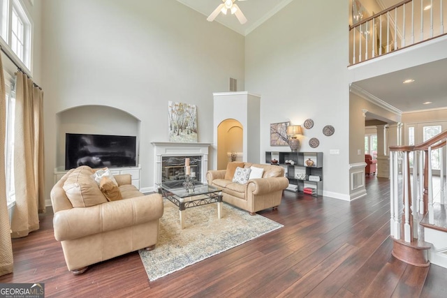 living area featuring baseboards, a glass covered fireplace, wood finished floors, and a towering ceiling