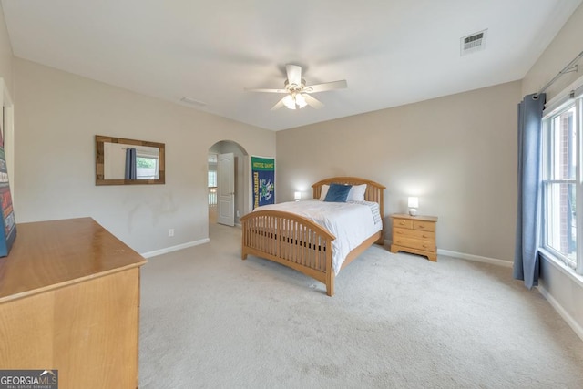 carpeted bedroom featuring visible vents, arched walkways, baseboards, and multiple windows