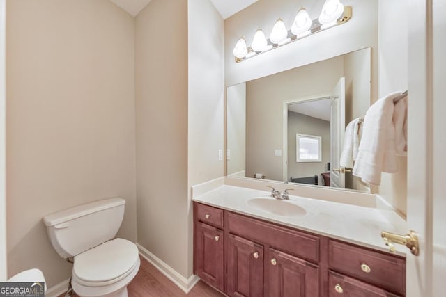 bathroom with baseboards, vanity, toilet, and wood finished floors