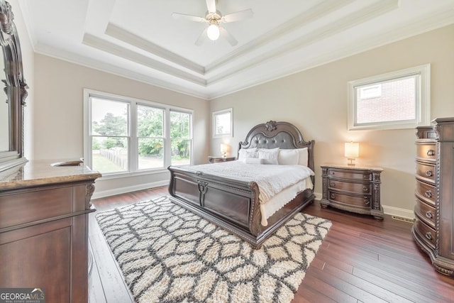 bedroom with ornamental molding, a ceiling fan, a tray ceiling, and dark wood-style floors