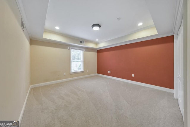spare room with carpet flooring, a tray ceiling, visible vents, and baseboards