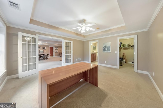unfurnished office featuring ceiling fan, light colored carpet, french doors, a tray ceiling, and visible vents